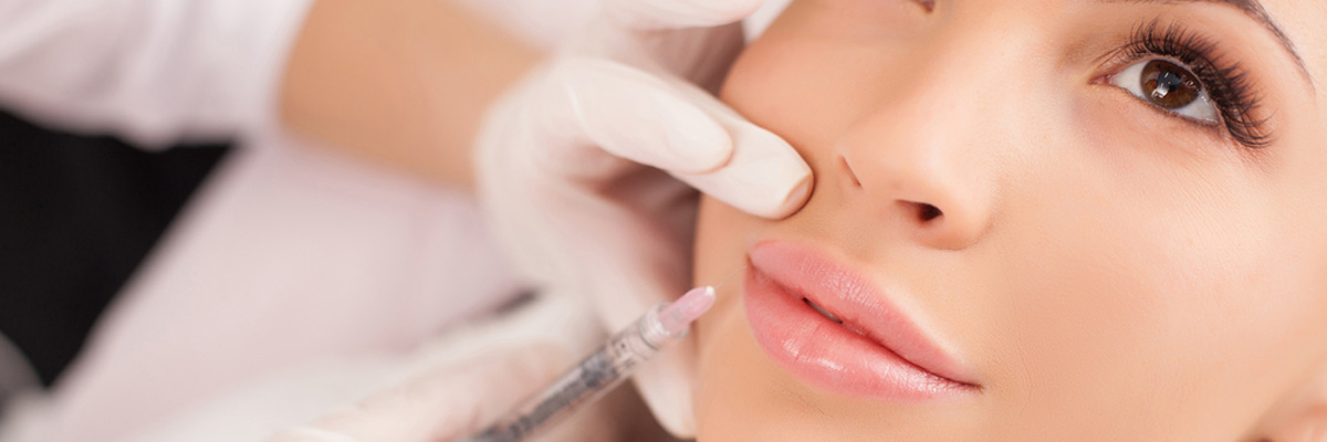 cosmetologist making botox injection in female lips