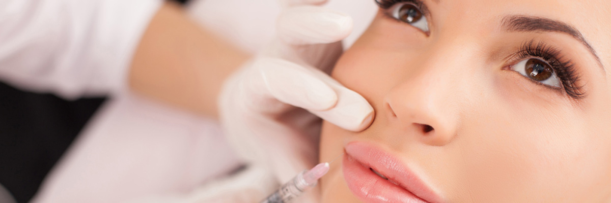Cosmetologist making botox injection in female lips